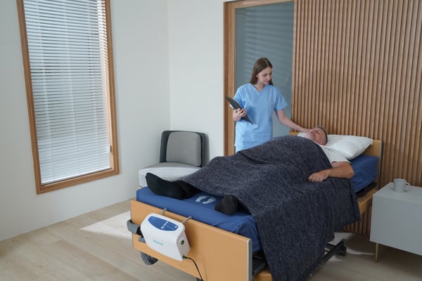 Caregiver observes a patient laying down on an mattress ( Domus 4 ) therapeutic support surface. 